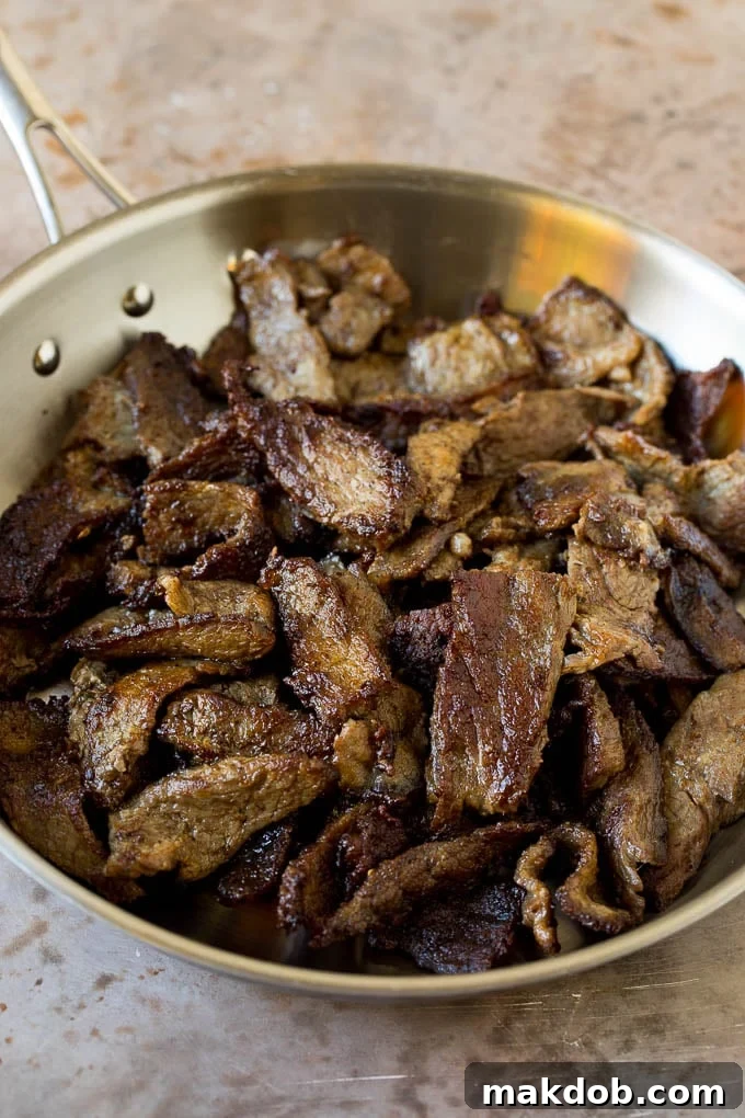 This kung pao beef is a combination of thinly sliced steak, bell peppers, onions and roasted peanuts, all in a savory and spicy sauce. Cooked sliced beef in a skillet.