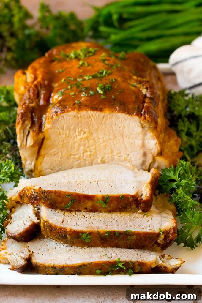 This crock pot pork roast is tender pork loin simmered in a slow cooker in a rich and flavorful gravy. Crock pot pork roast sliced on a serving plate, garnished with fresh herbs.