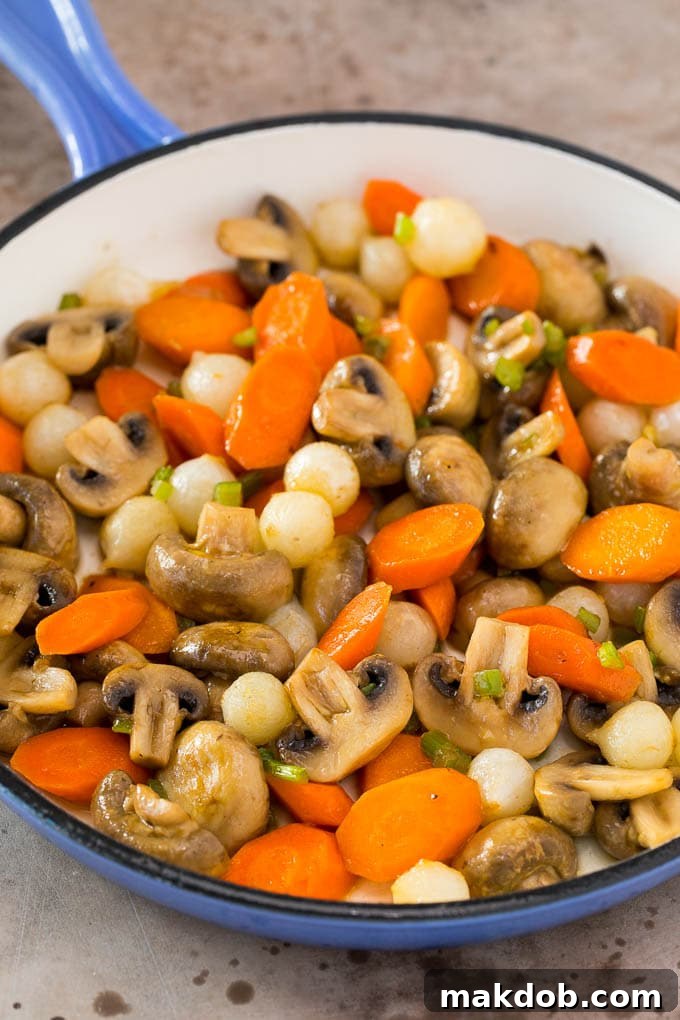 Mushrooms, carrots and pearl onions in a pan.