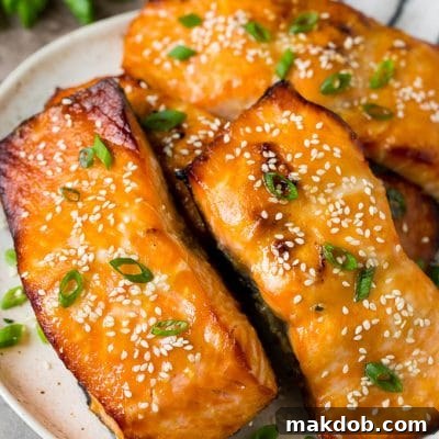 A platter of miso salmon fillets topped with sesame seeds and green onions.