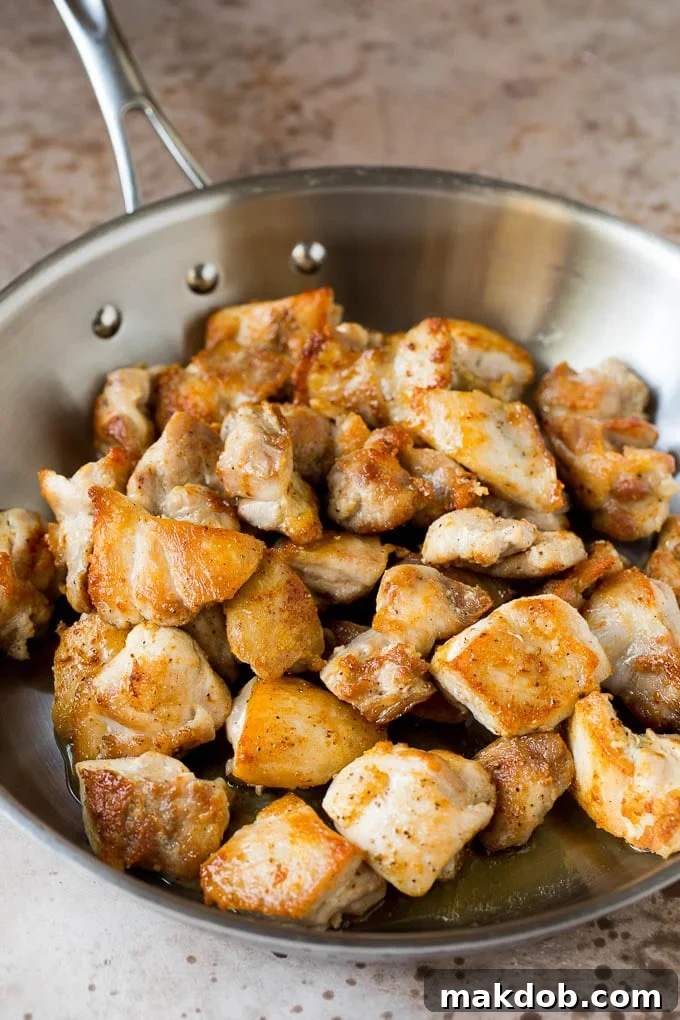 Seared chicken thigh pieces in a pan.