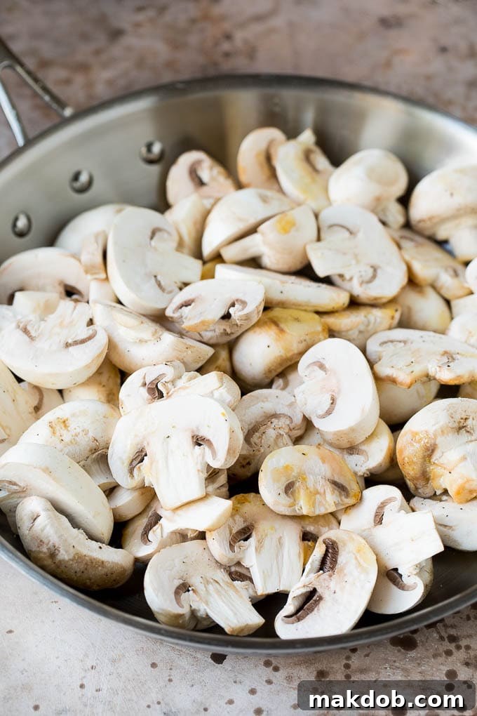 Raw sliced mushrooms in a skillet.