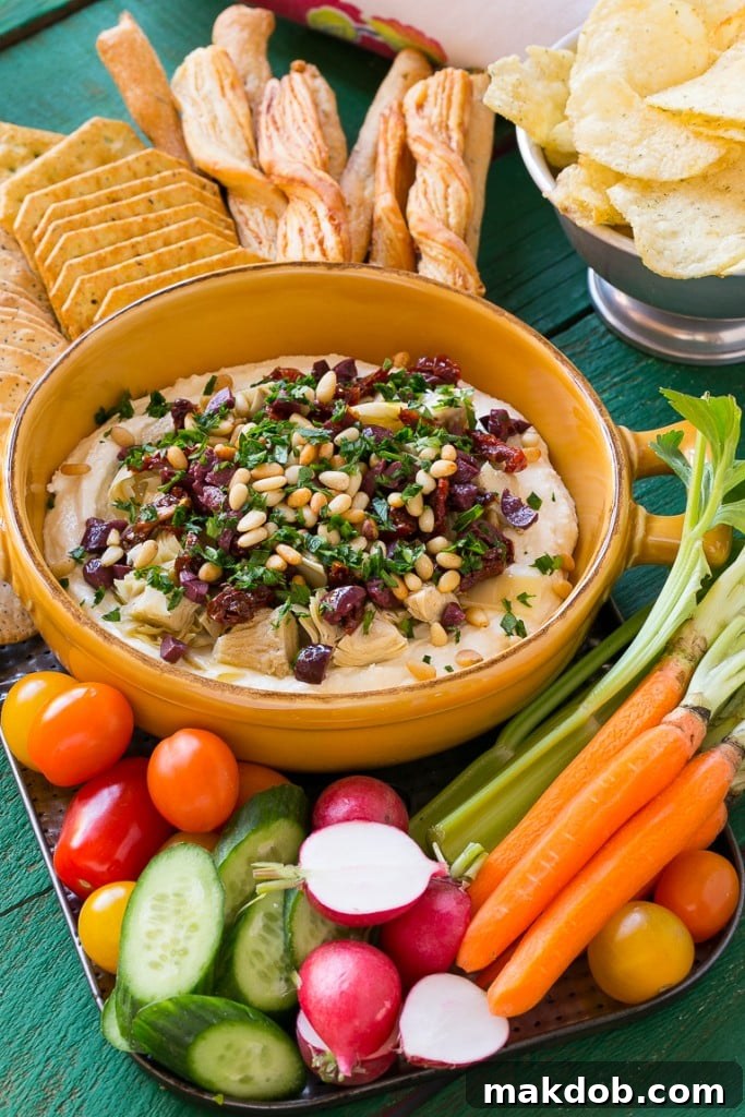 A close-up side view of the Mediterranean Layered Dip, highlighting the distinct layers of creamy feta, dark olives, and vibrant red sun-dried tomatoes, illustrating its rich texture.