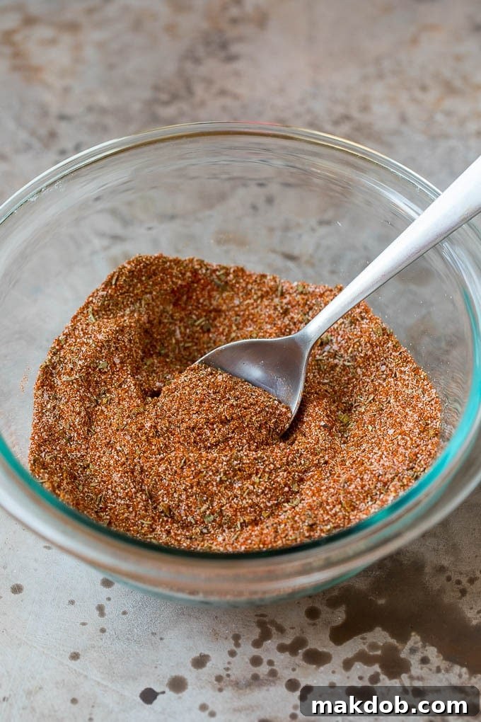 Perfecting Your Spice Blend A beautiful mix of vibrant spices in a bowl with a spoon, showcasing the rich colors of homemade blackened seasoning.