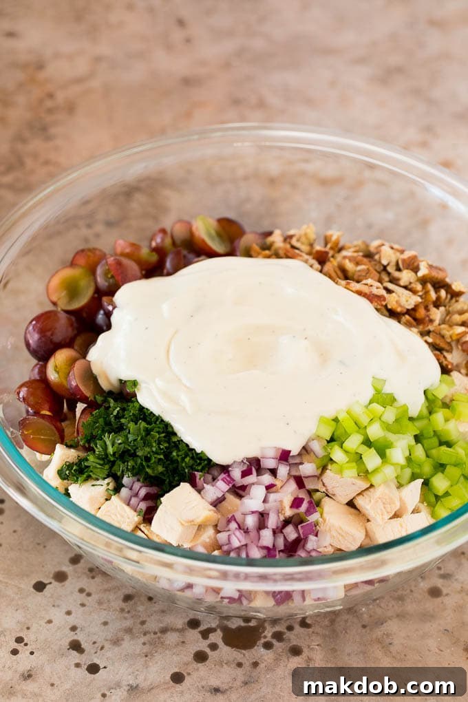 Creamy dressing poured over diced chicken and vegetables in a mixing bowl.