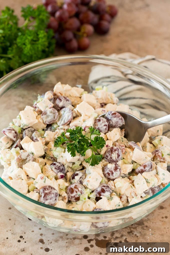 A bowl of chicken salad with grapes, garnished with fresh parsley, ready to serve.