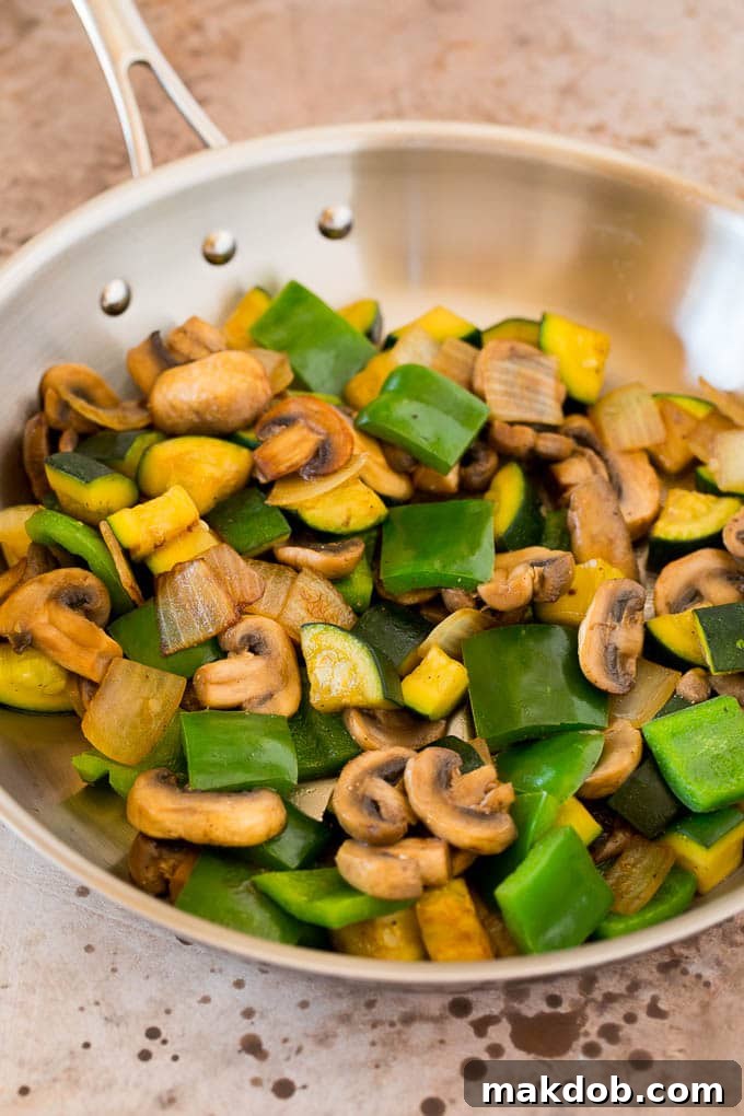 Mushrooms, zucchini and bell peppers cooked in a pan.