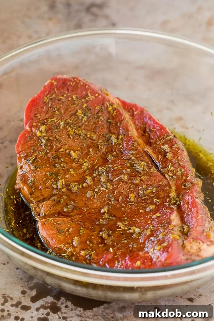 London broil marinade in a bowl with a piece of steak in it.