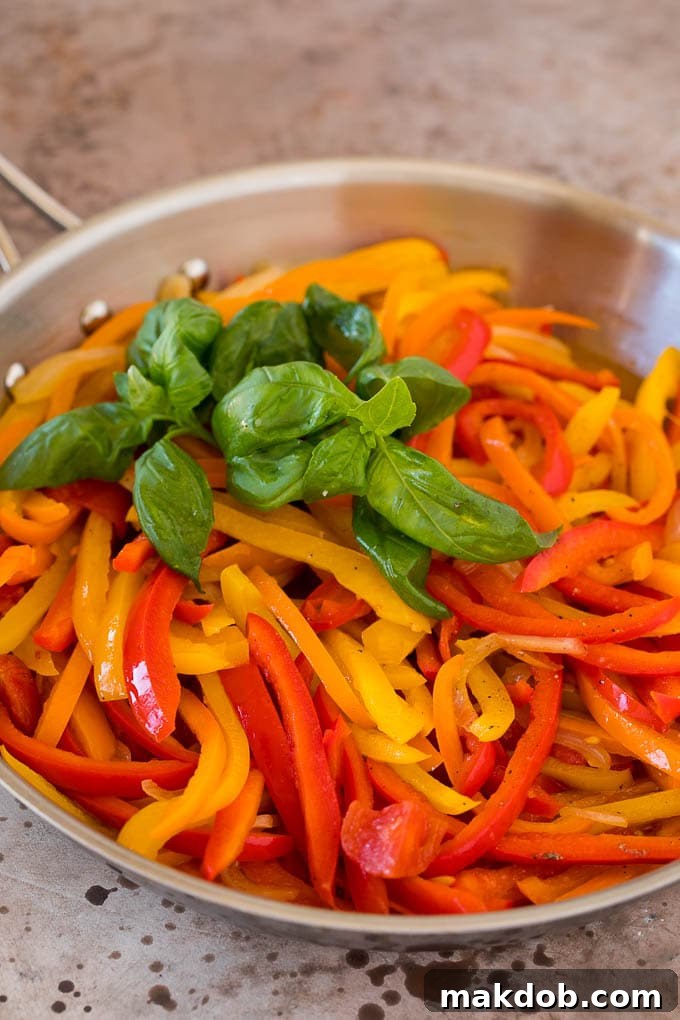 Garnished peperonata ready to serve A close-up of tender, stewed bell peppers and onions, beautifully garnished with vibrant fresh basil leaves, ready to be served.