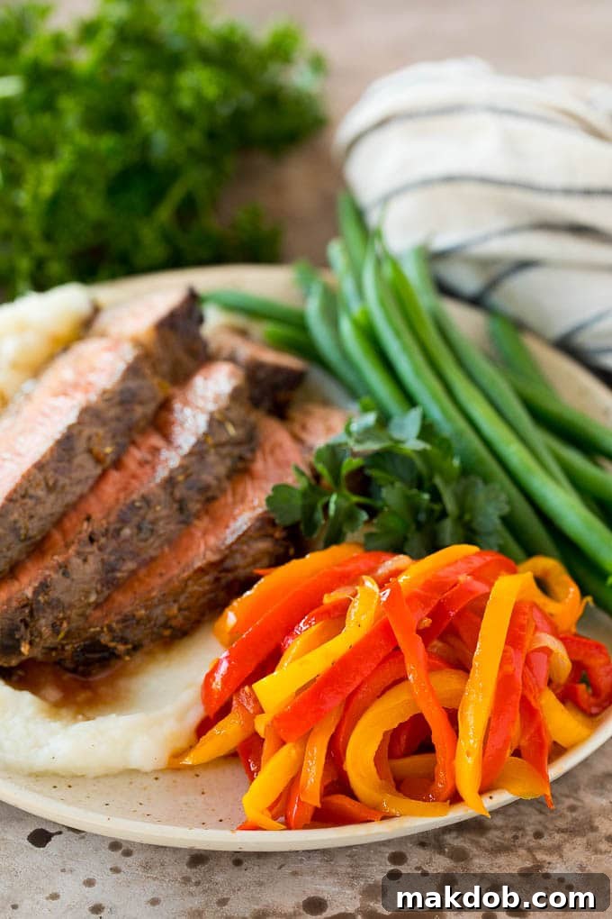 Peperonata served as a delicious side with steak A satisfying serving of peperonata, brimming with colorful stewed peppers, onions, and tomatoes, perfectly paired with a juicy grilled steak and crisp green beans.