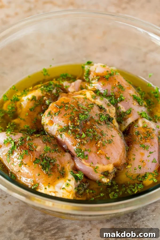 Chicken thighs absorbing rich flavors in a bowl of marinade. Raw chicken thighs in a bowl of marinade, ready for refrigeration.