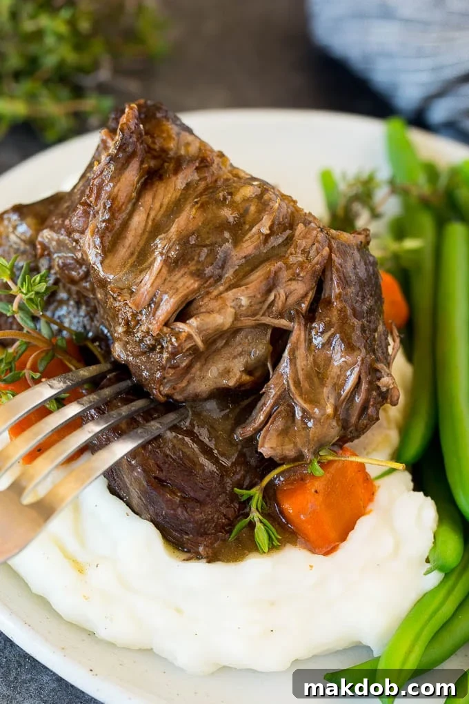 A plate of tender Instant Pot short ribs served over creamy mashed potatoes, garnished with fresh herbs.