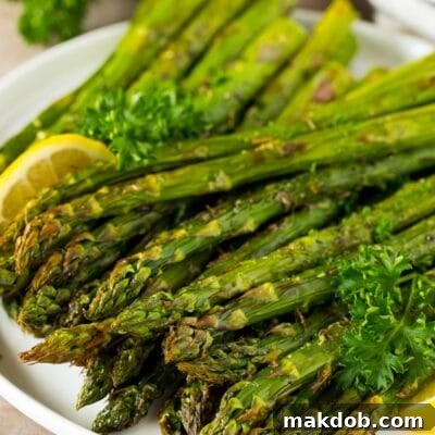 A plate of air fryer asparagus garnished with lemon and parsley.