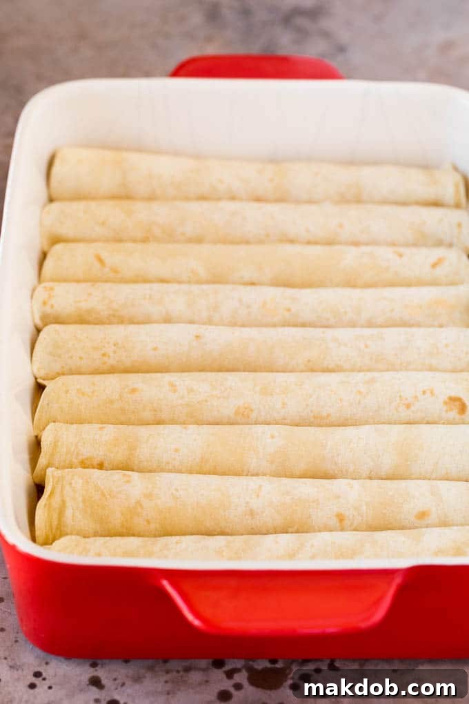This recipe for cheese enchiladas is rolled flour tortillas filled with cheddar and Monterey Jack cheeses, then topped with red sauce and more cheese and baked to golden brown perfection. Cheese rolled up inside tortillas in a dish.