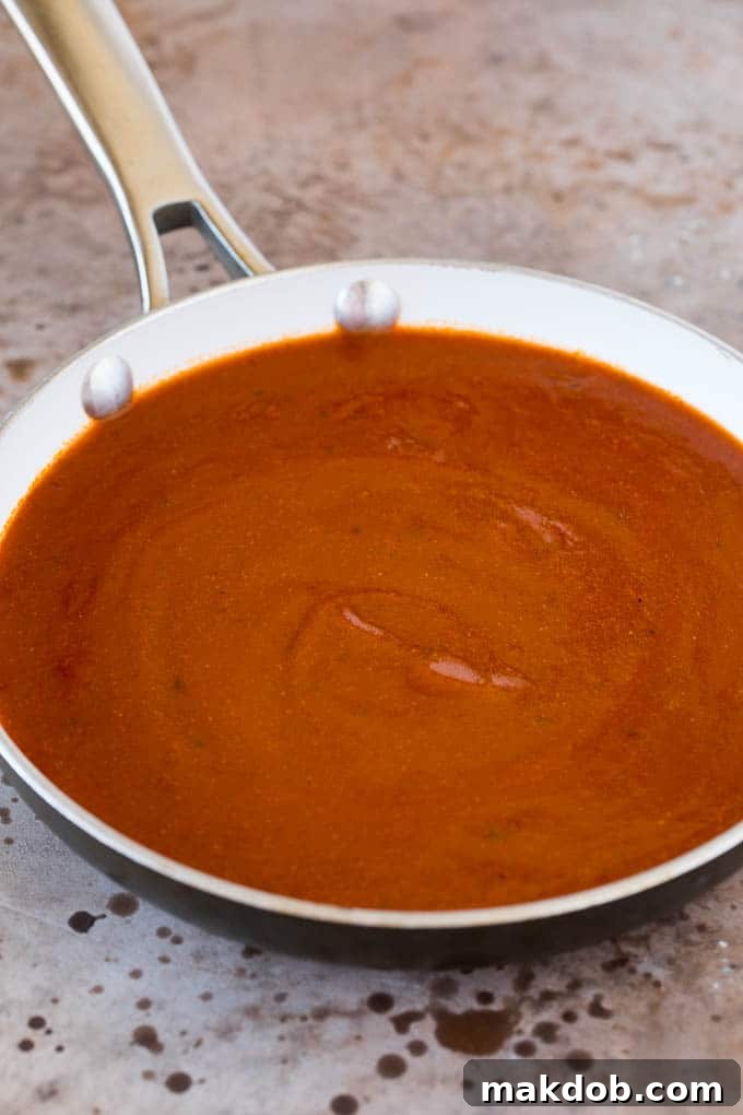 Simmering Enchilada Sauce Chicken broth, seasonings, and tomato sauce simmering together in a pan for enchilada sauce.