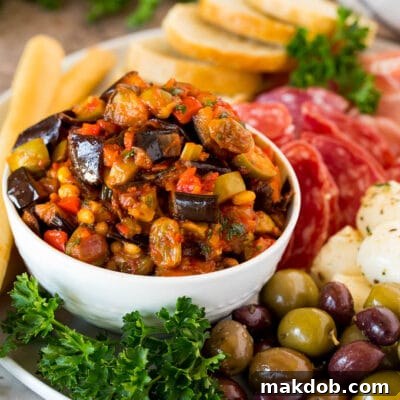 A bowl of eggplant caponata served with olives, cured meats and bread.