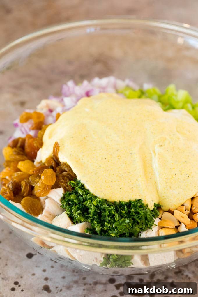 A bowl of curry chicken salad with a rich, creamy dressing poured over the top, highlighting its luscious texture.