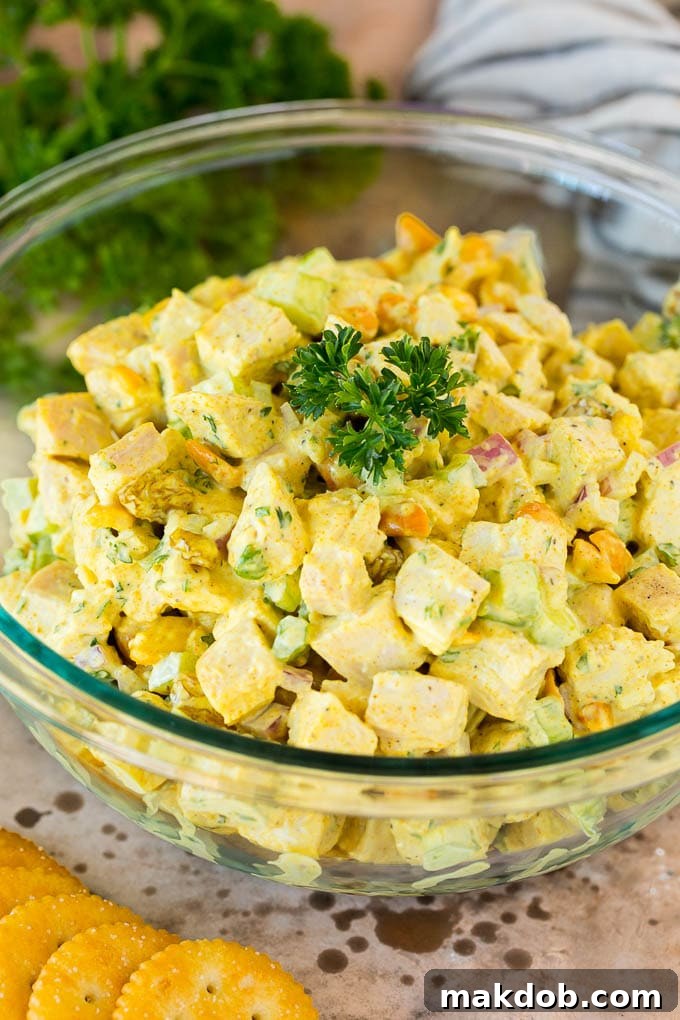 A beautifully presented serving bowl of curry chicken salad, garnished with fresh parsley for a touch of elegance and flavor.
