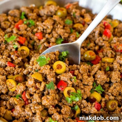 A pan of picadillo with a serving spoon in it.