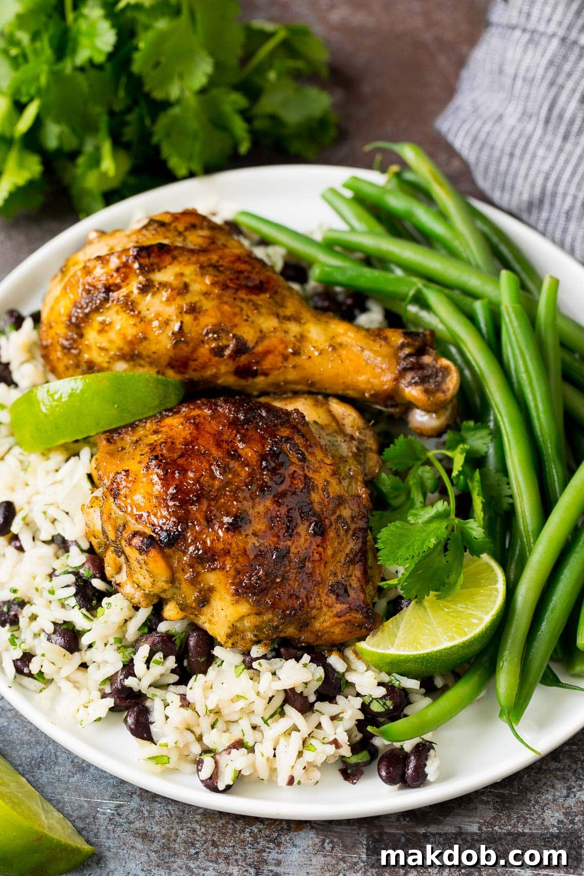 Perfectly cooked jerk chicken, coated in homemade seasoning, served alongside a vibrant dish of rice and beans, showcasing a delicious and complete Caribbean meal.