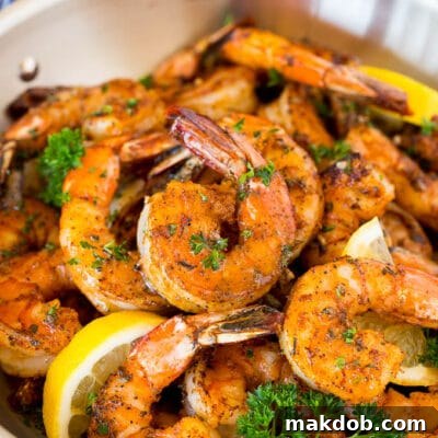A pan of Cajun shrimp garnished with parsley and lemon.
