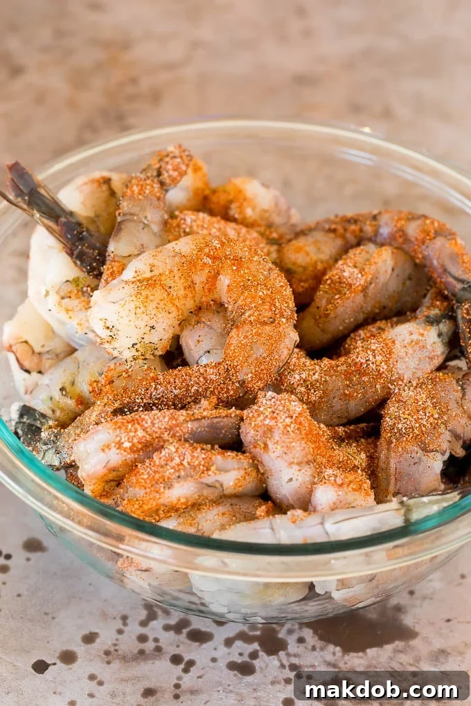 A bowl of raw shrimp coated in seasonings.