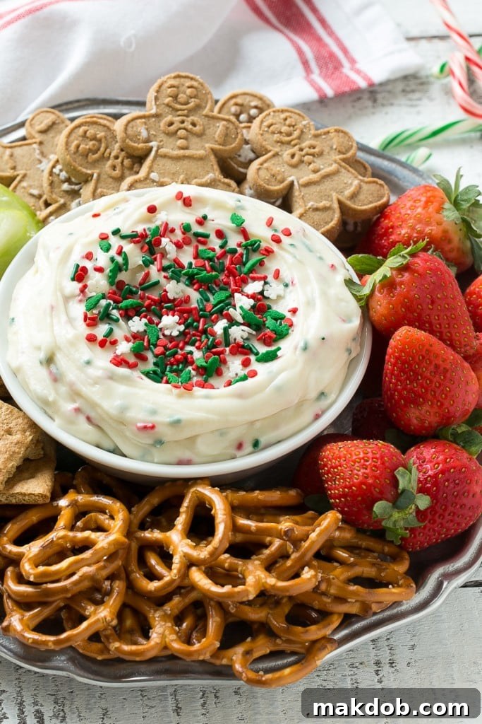 Magical Christmas Cookie Dough Dip 4 An overhead shot of the Christmas Cookie Dough Dip in a festive bowl, surrounded by a variety of dippers including apple slices, graham crackers, and pretzels.