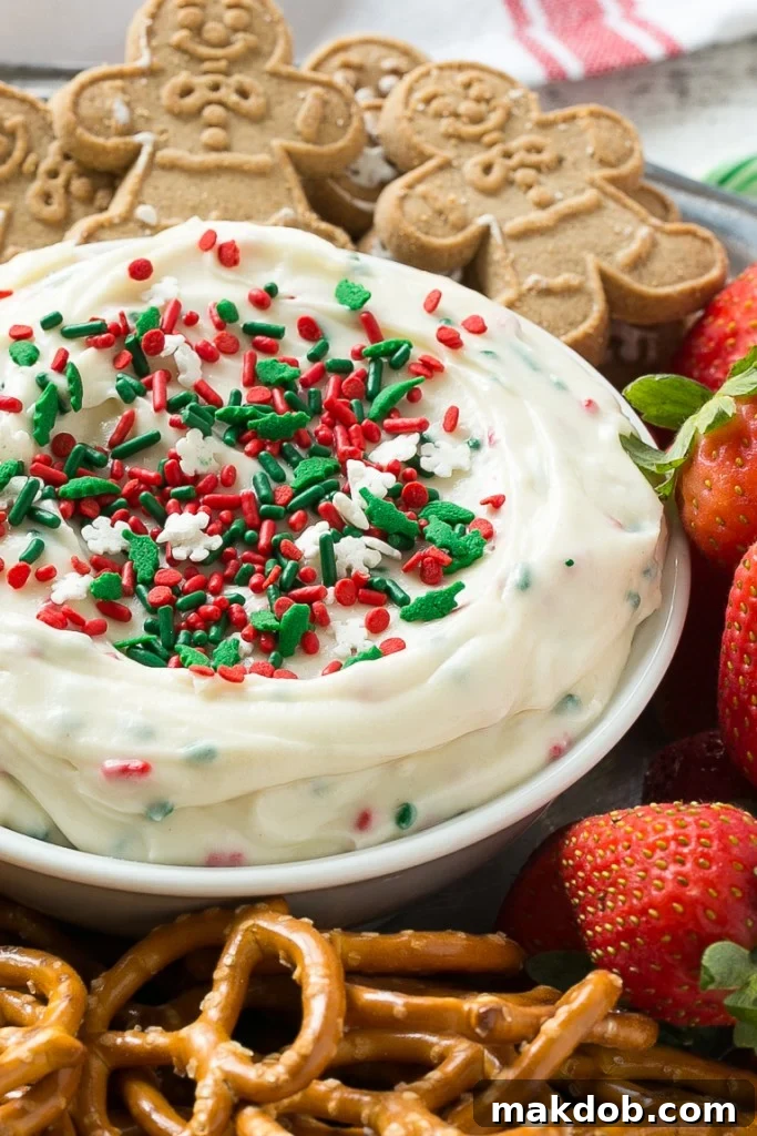 Magical Christmas Cookie Dough Dip 6 A vibrant display of Christmas Cookie Dough Dip surrounded by various dippers, including fresh fruit, pretzels, and cookies, ready for a festive gathering.