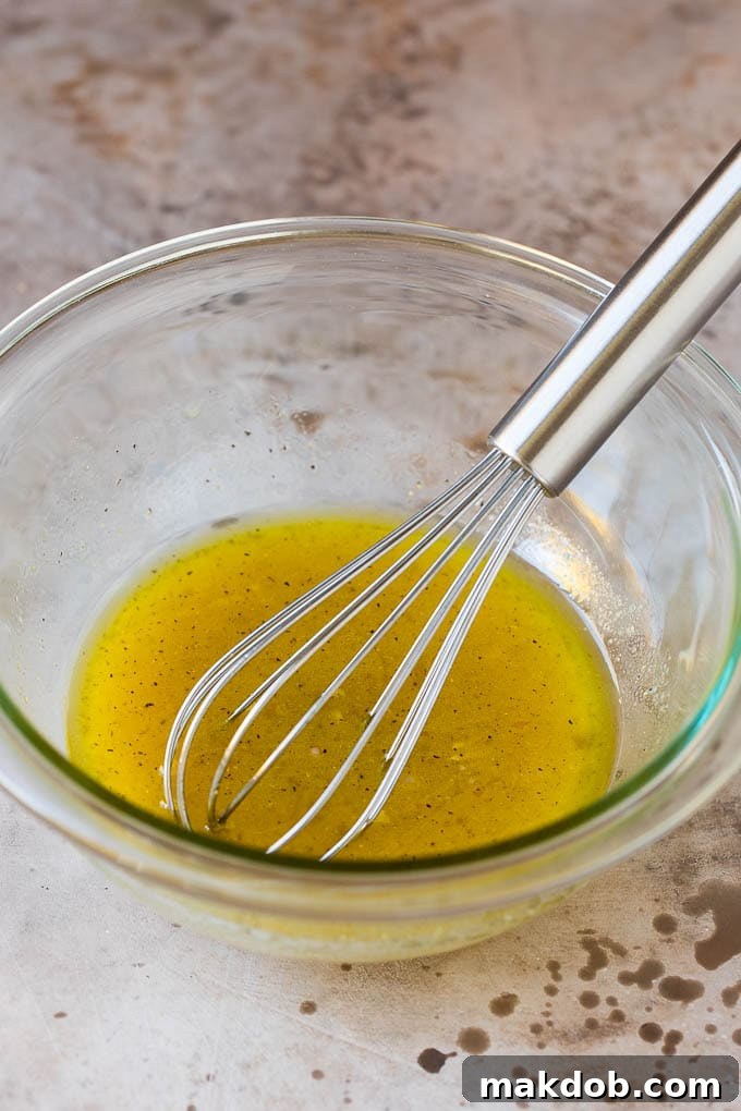 A bowl of salad dressing with a whisk in it.