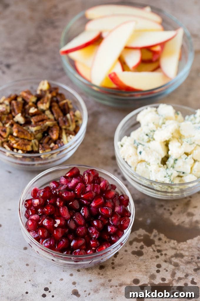 Bowls of cheese, pomegranate arils, apples and pecans.