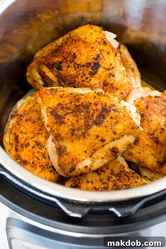 Seared chicken thighs in a pressure cooker, before the lid is sealed.