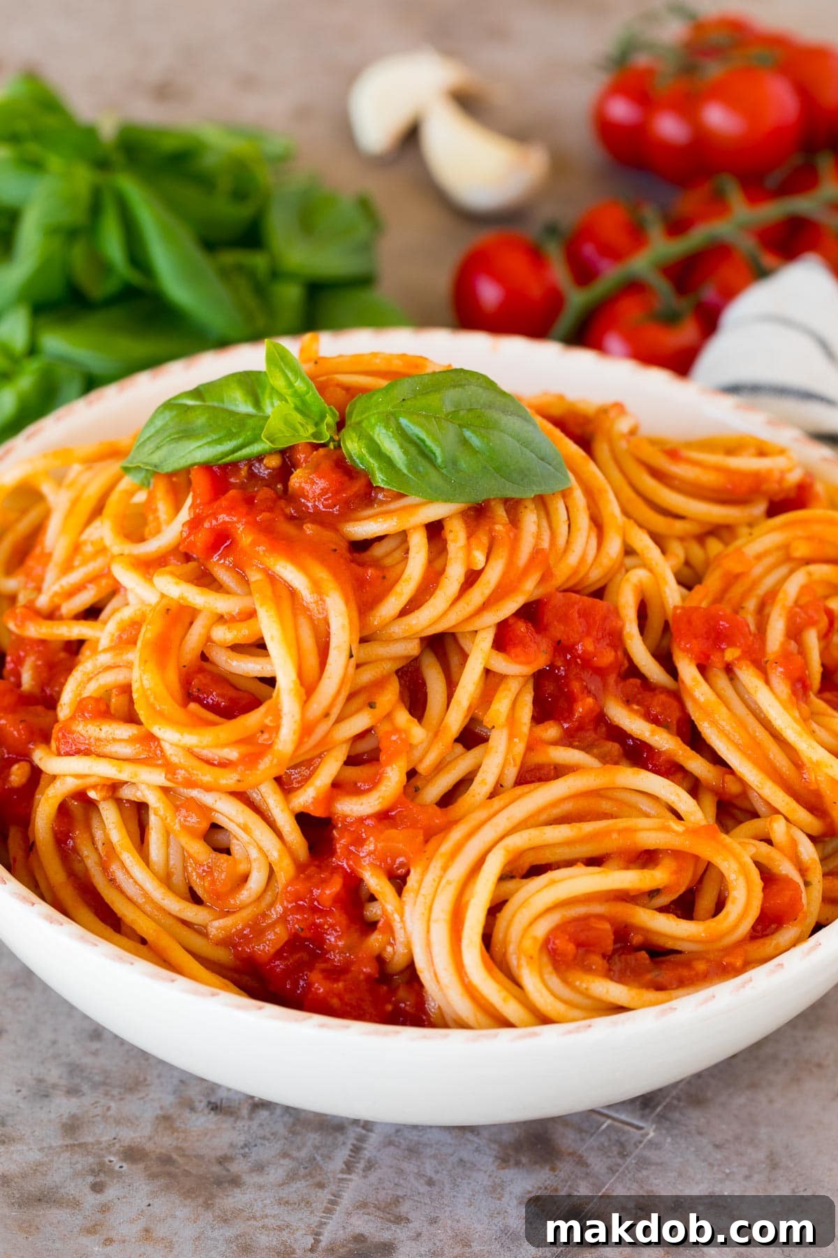 Robust Homemade Marinara 6 Spaghetti tossed with vibrant homemade marinara sauce in a white bowl, garnished with fresh basil leaves, ready to be served.