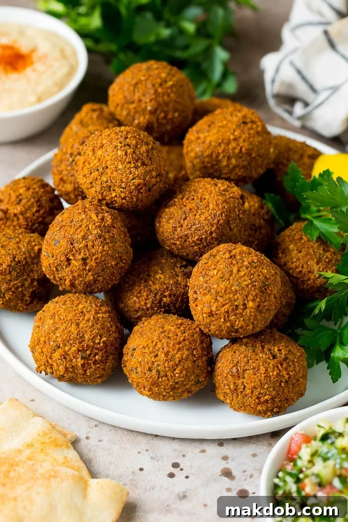 A beautifully arranged platter of golden-brown falafel garnished with fresh parsley and lemon wedges, ready to be served.