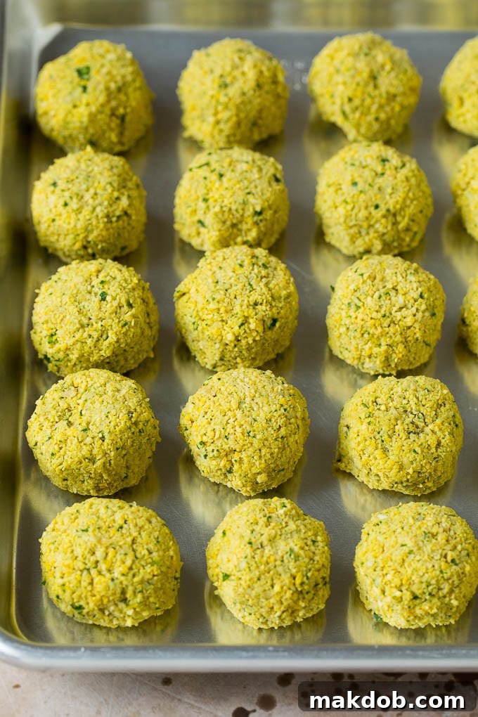Perfectly portioned balls of raw chickpea paste, meticulously formed and arranged, ready for their transformation into crispy falafel through frying.