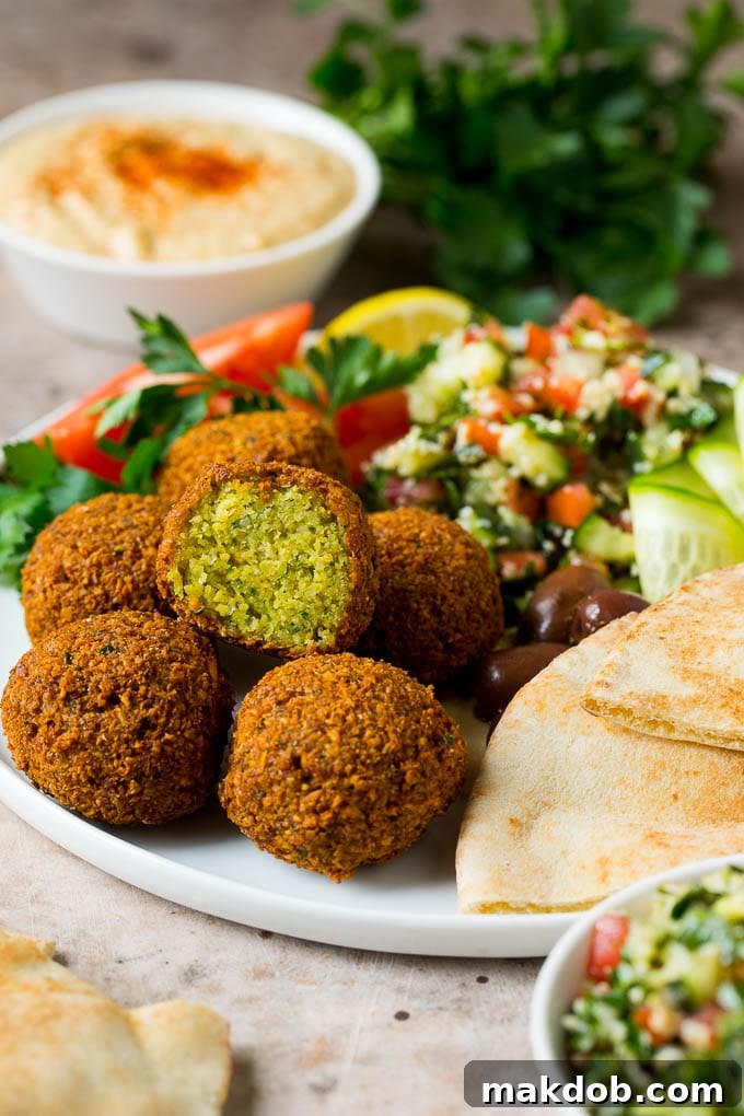 A vibrant platter showcasing golden-brown falafel balls, accompanied by fresh olives, a crisp green salad, and warm pita bread, invitingly arranged for a Mediterranean meal.