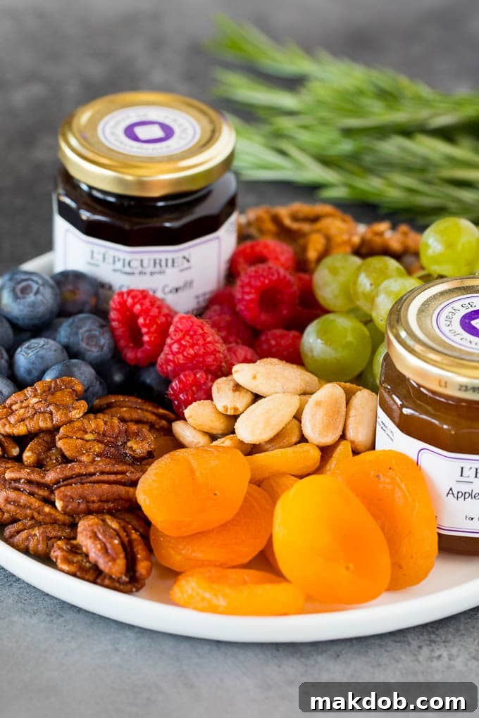 A plate with fresh and dried fruit, nuts and jam.