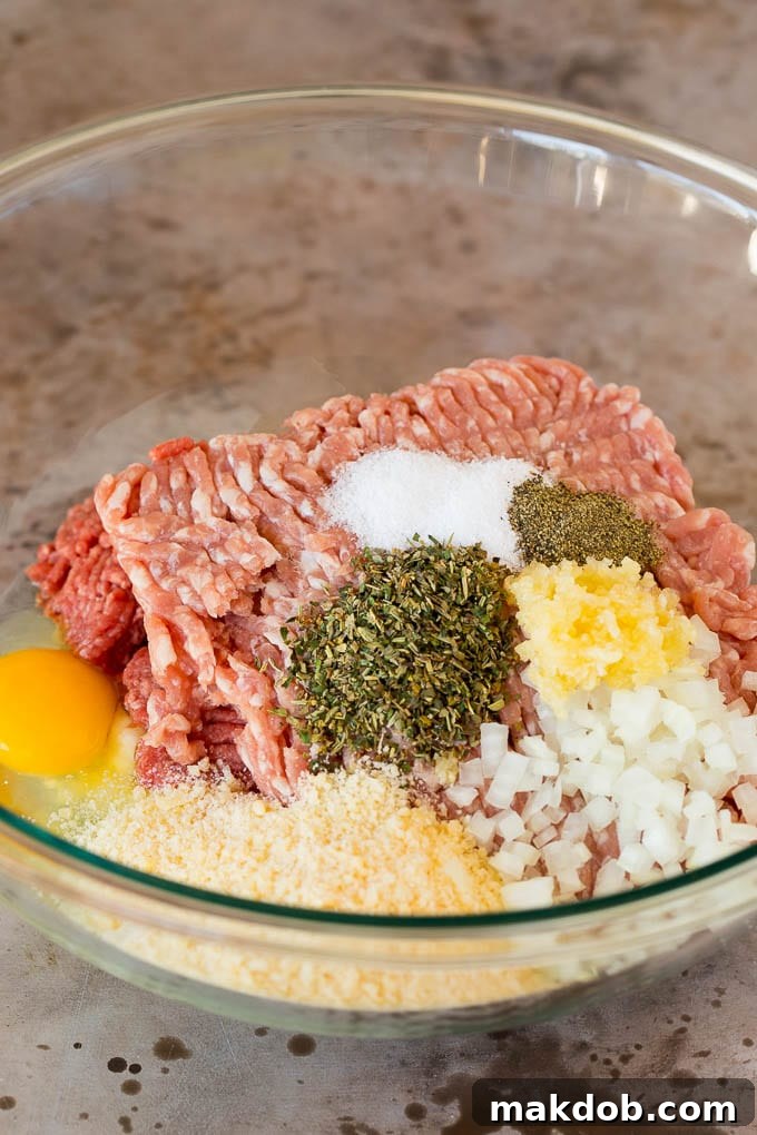 Ground beef, ground pork, and Italian seasonings ready for mixing in a large bowl.