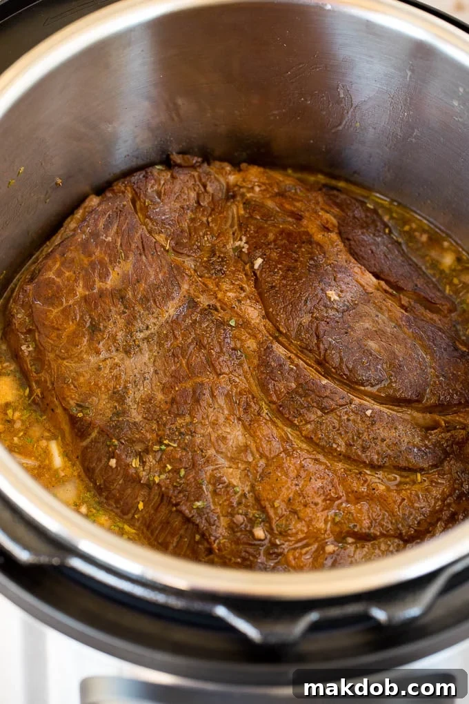 A perfectly seared chuck roast resting in an Instant Pot, ready for the next steps in creating a delicious pot roast.