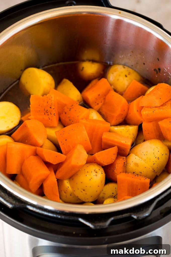 Carrots and potatoes prepped and ready to be added to a pressure cooker, alongside the cooked beef.