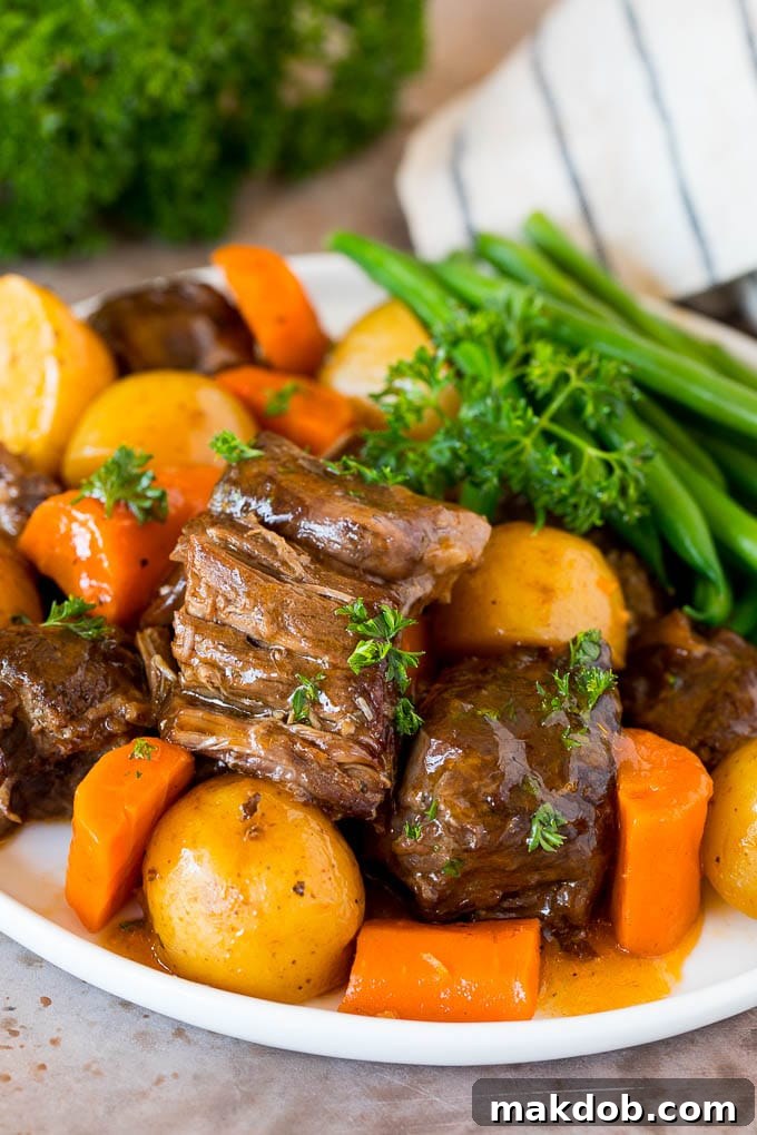 A plate of Instant Pot pot roast served with tender carrots, green beans, and potatoes, generously topped with savory gravy.