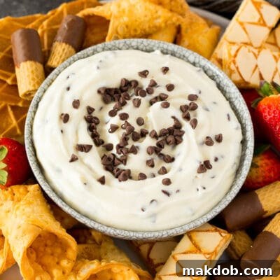 Deconstructed Cannoli Dip 2 A bowl of cannoli dip surrounded by cookies, cannoli shells and strawberries.