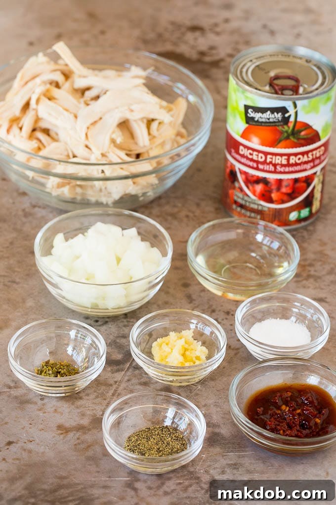 This chicken tinga is a classic dish made with shredded chicken that's simmered in a smoky and savory sauce. Bowls of ingredients such as chicken, spices, onions and garlic.