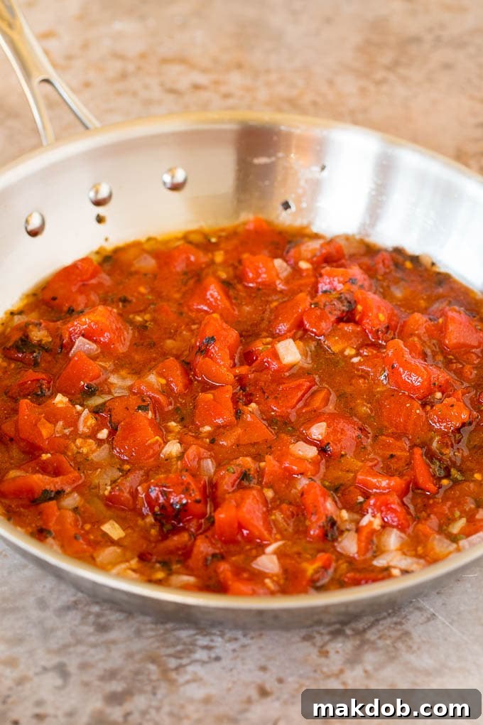 This chicken tinga is a classic dish made with shredded chicken that's simmered in a smoky and savory sauce. A pan of tomatoes, onions, garlic and herbs.