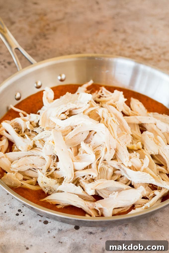 This chicken tinga is a classic dish made with shredded chicken that's simmered in a smoky and savory sauce. Shredded chicken in a pan of tomato sauce.
