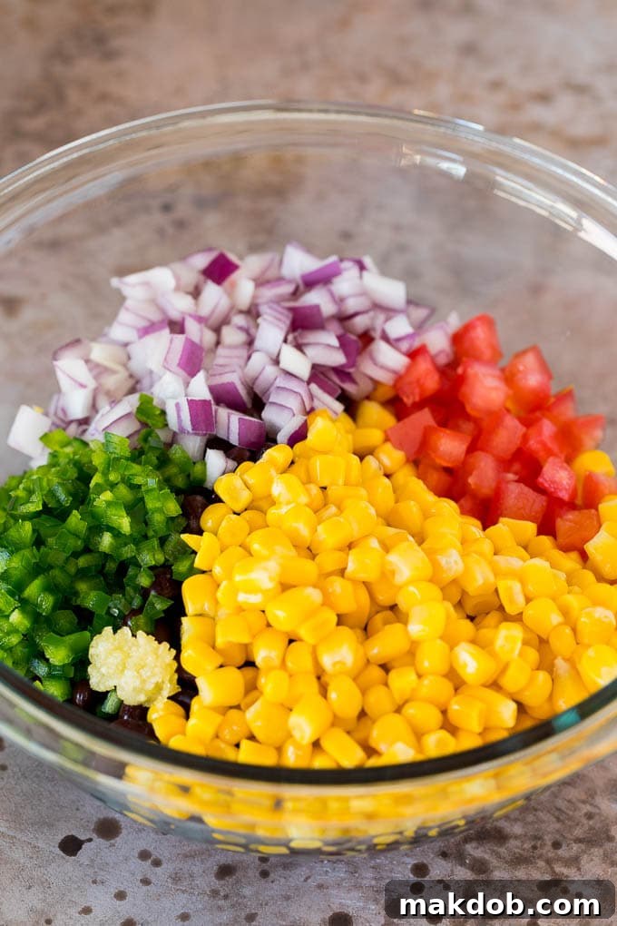 Corn, tomatoes, jalapeno and red onion in a bowl.