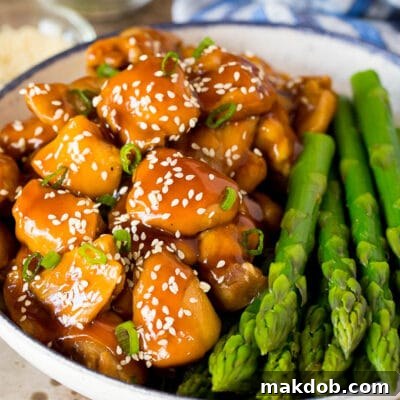 Sticky Sweet Instant Pot Teriyaki Chicken 2 Instant Pot teriyaki chicken served with asparagus, garnished with sesame seeds and green onions.