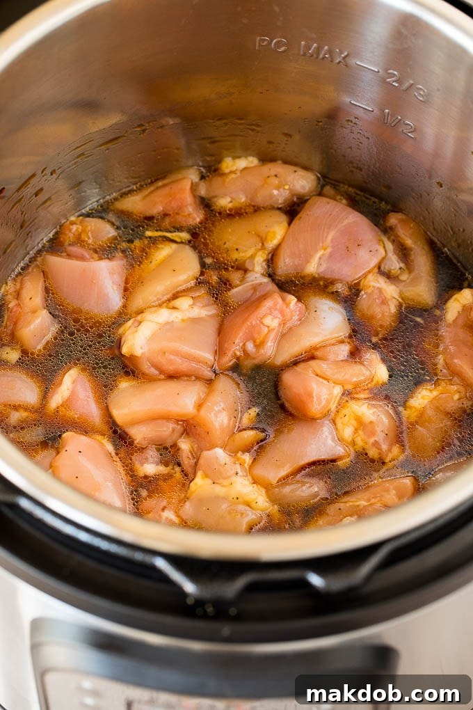 The Instant Pot works its magic, simmering chicken in the fragrant teriyaki sauce. Chicken and sauce simmering in a pressure cooker after cooking, ready for thickening.