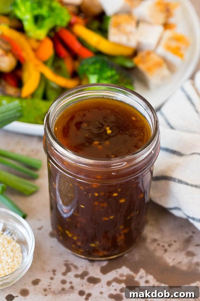 Homemade Teriyaki Sauce: Your Ultimate Sweet and Savory Condiment A jar of homemade teriyaki sauce shown next to a plate of vibrant stir-fried vegetables and perfectly grilled teriyaki chicken.