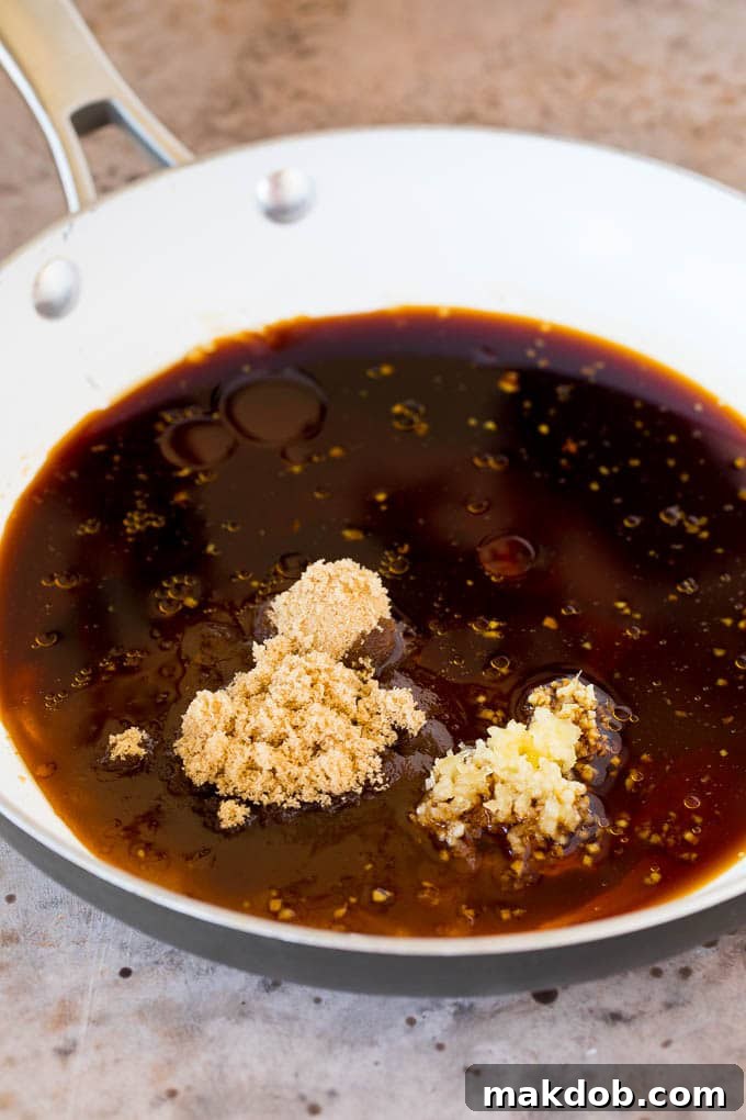 Simmering Teriyaki Sauce Ingredients A pan filled with the simmering base ingredients for teriyaki sauce: soy sauce, garlic, ginger, brown sugar, and honey, ready to be thickened.