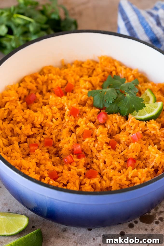 A pot of vibrant Mexican rice garnished with fresh tomatoes, fragrant cilantro, and zesty lime wedges, ready to be served.